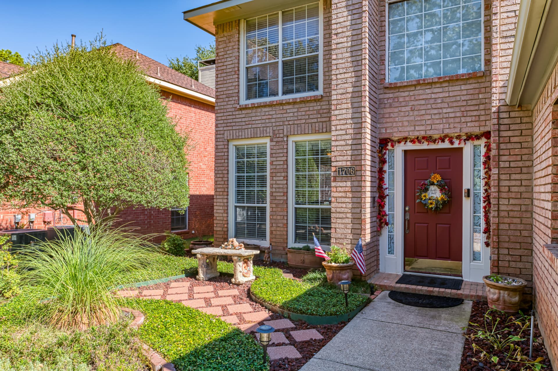 Landscaped front garden with stepping-stone path, stone bench and walkway to the red front door