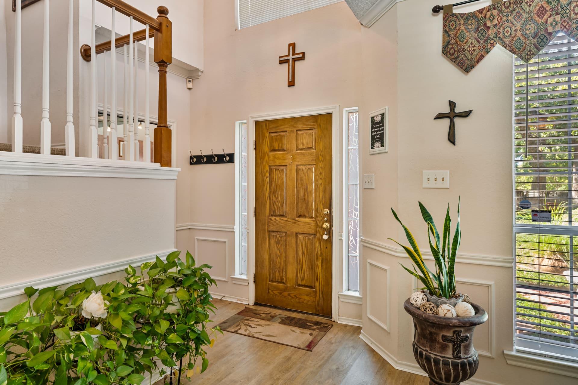 Bright two-story entry with wood front door, sidelights, wainscoting and wood-look flooring