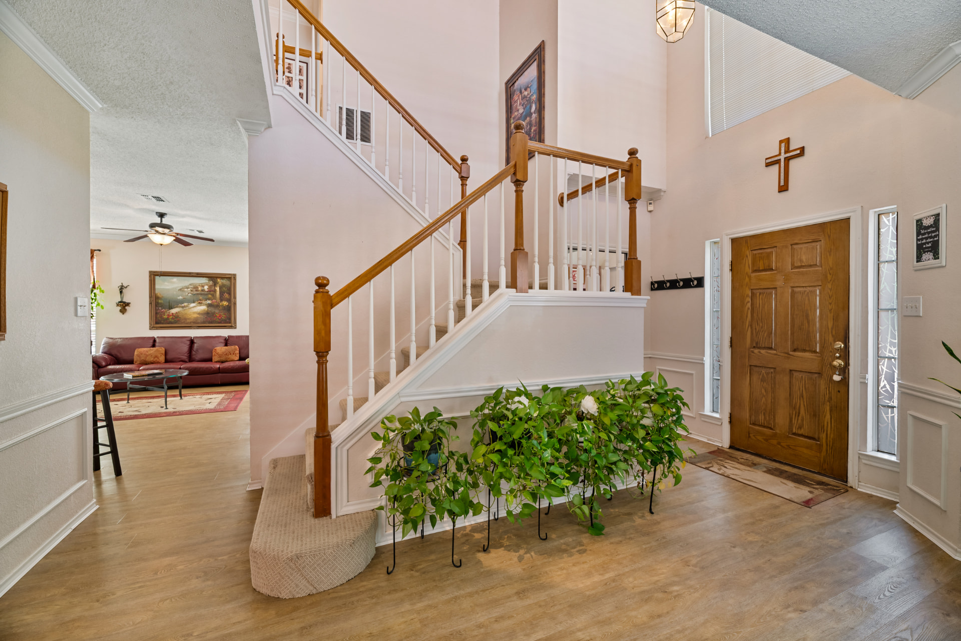 Soaring foyer with oak-railed staircase opening to the living room